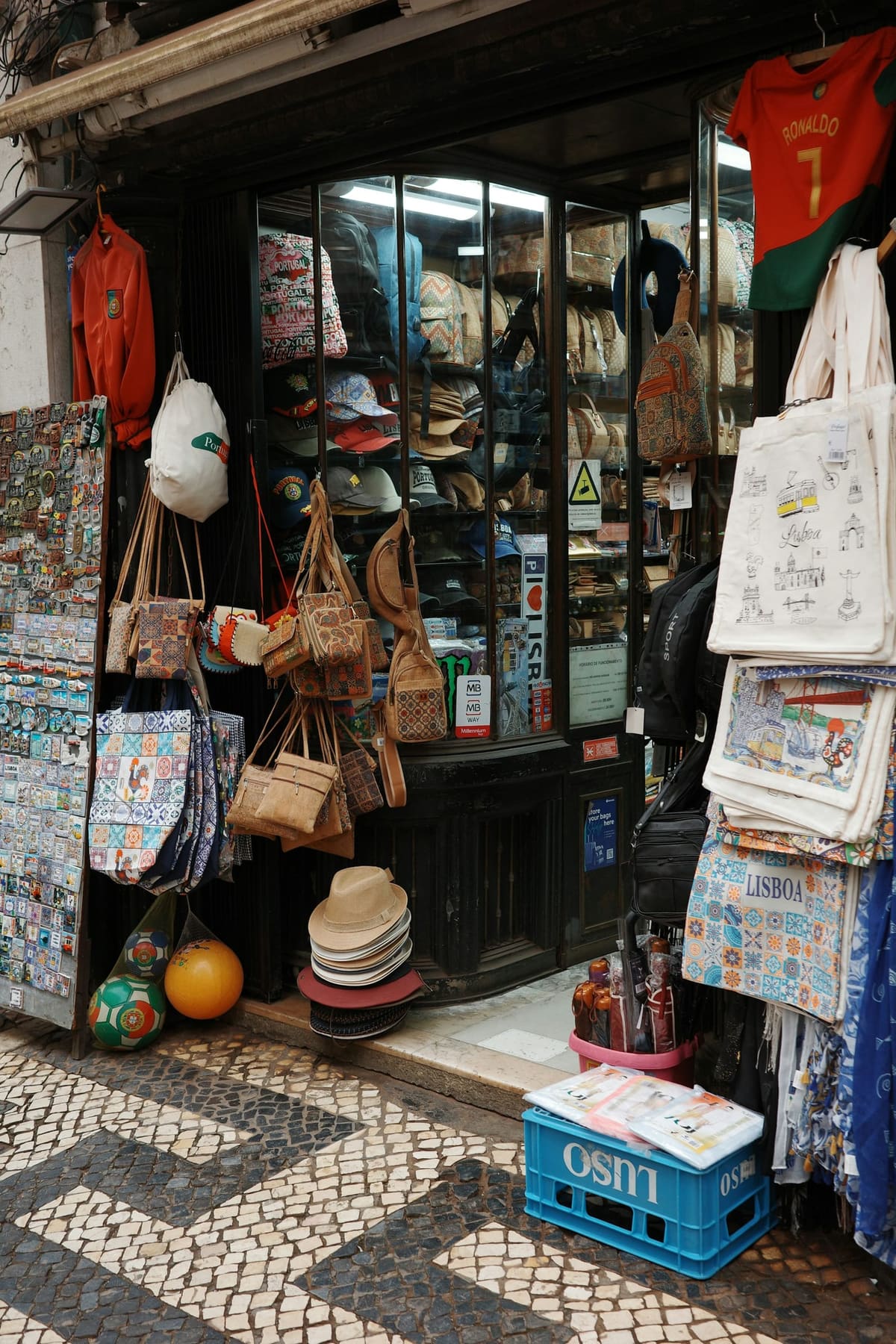Montra de uma loja de retalho em Lisboa, com produtos à porta sobre calçada portuguesa